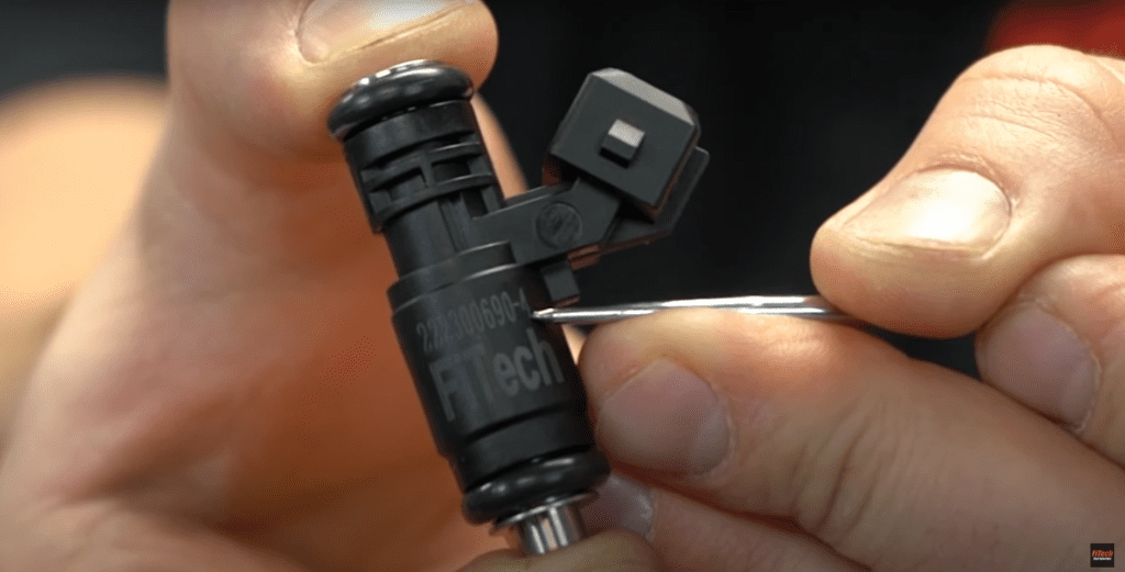 Close-up of a hand holding a small black mechanical part.