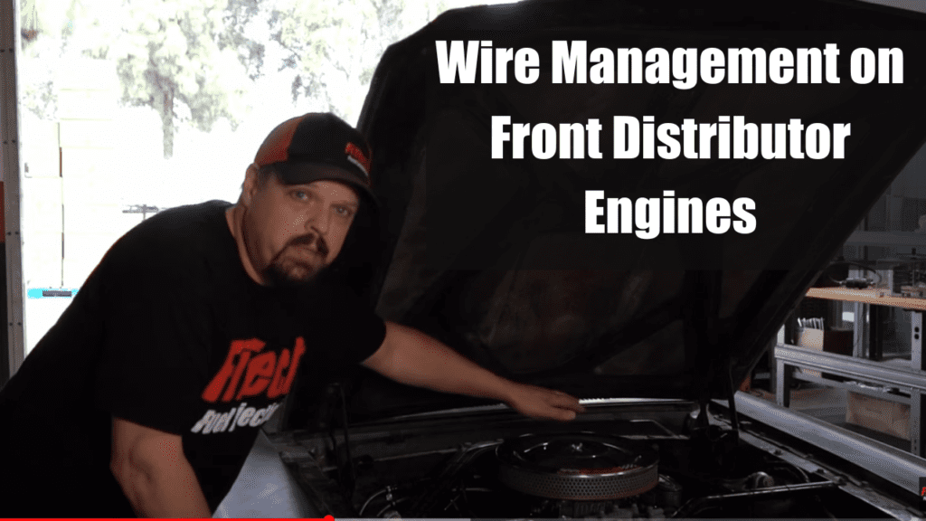Man working on car engine, focusing on wiring management.
