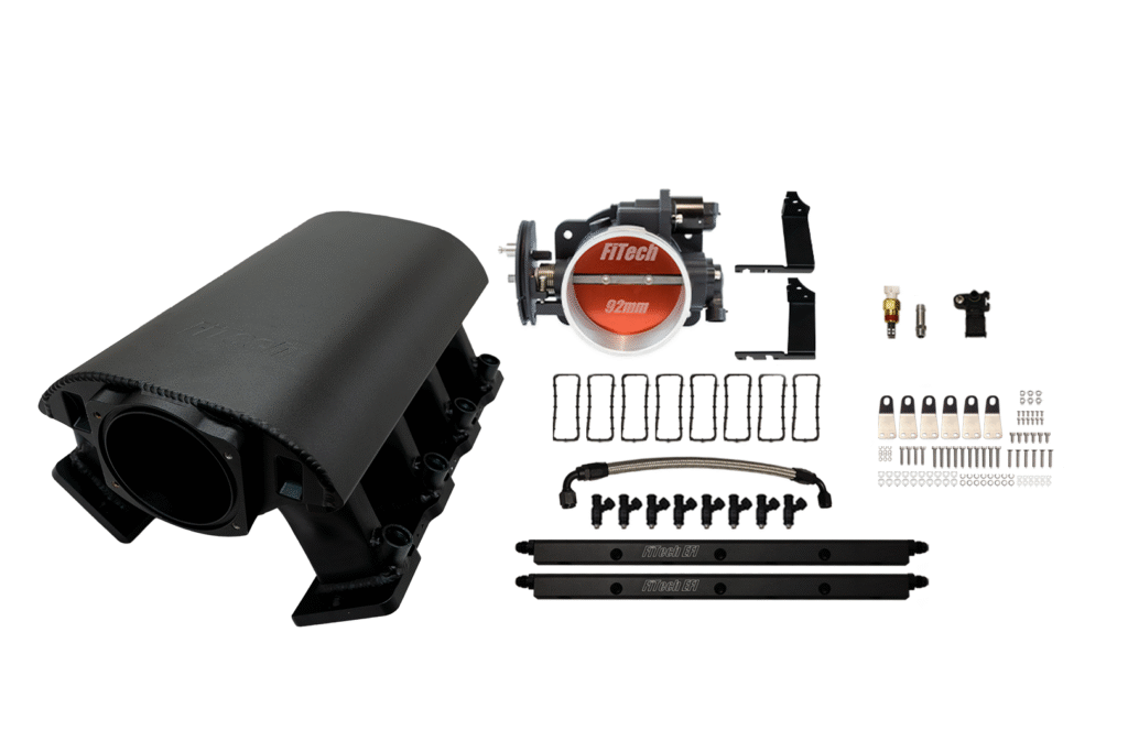 Car engine ignition coil and related components laid out on a white surface.