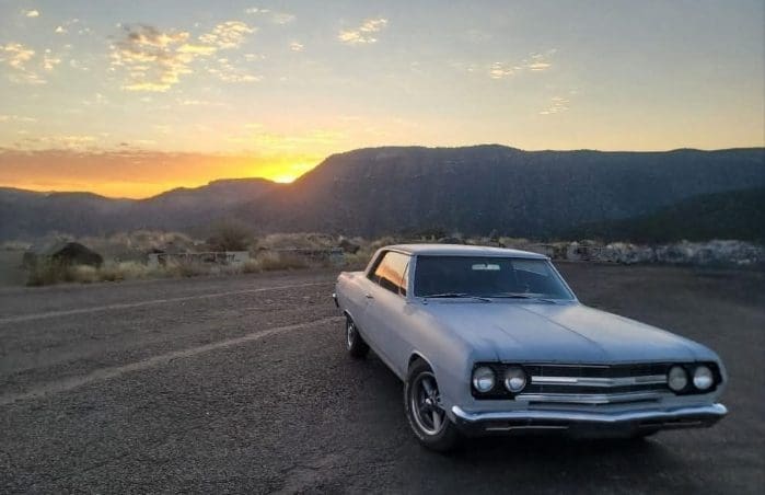 Classic car parked at sunset mountain view.