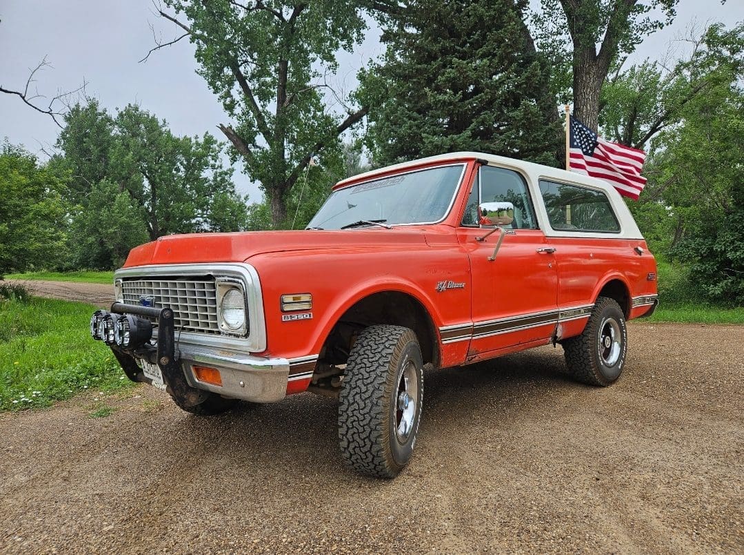 Red vintage SUV with American flag behind.
