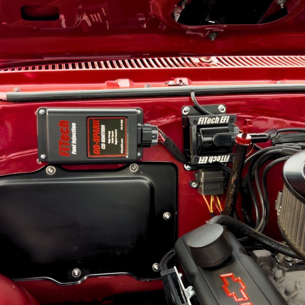FiTech EFI ignition components mounted in a red Chevrolet engine bay